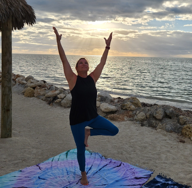 julianne-fitness-instructor woman doing yoga pose "tree' while on a beach